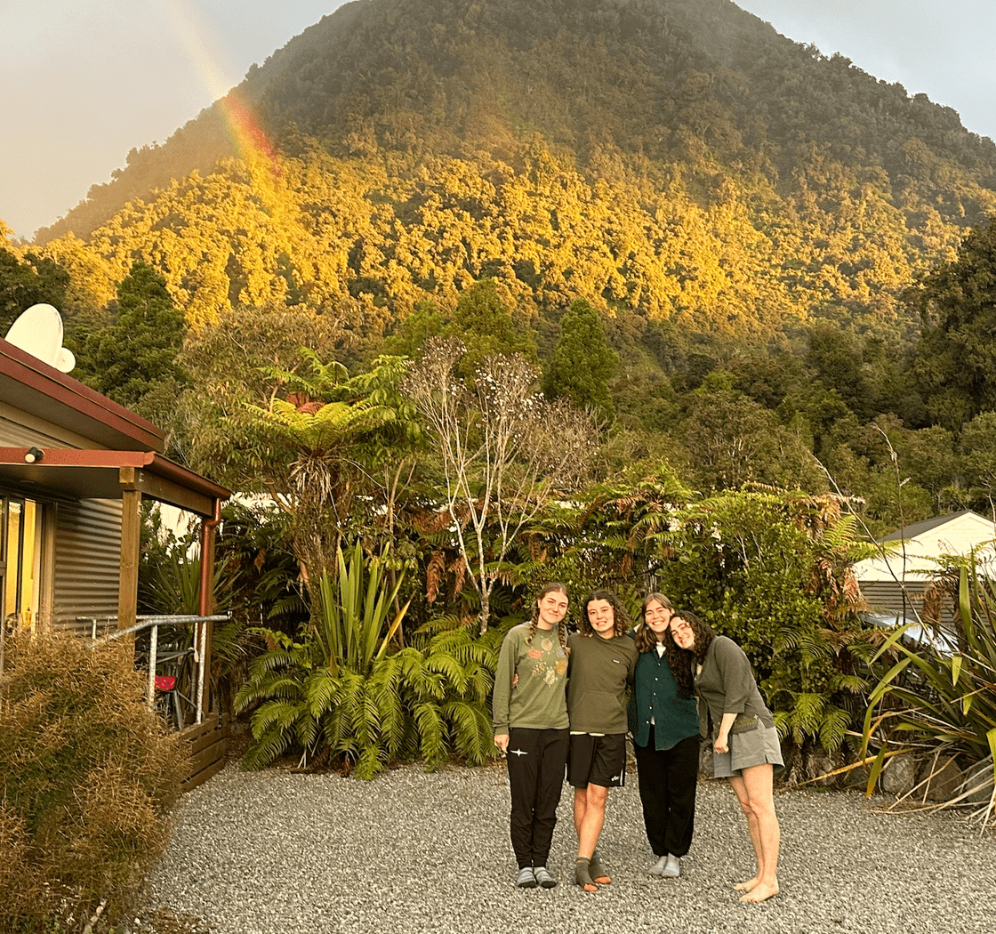 Catching a rainbow! Posing in front of rainbow and grassy mountain